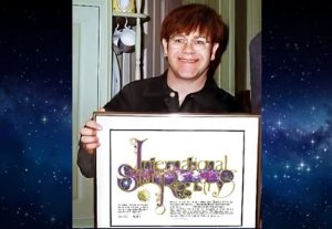 Image of Elton John holding his framed star gift for when he had a star named after him
